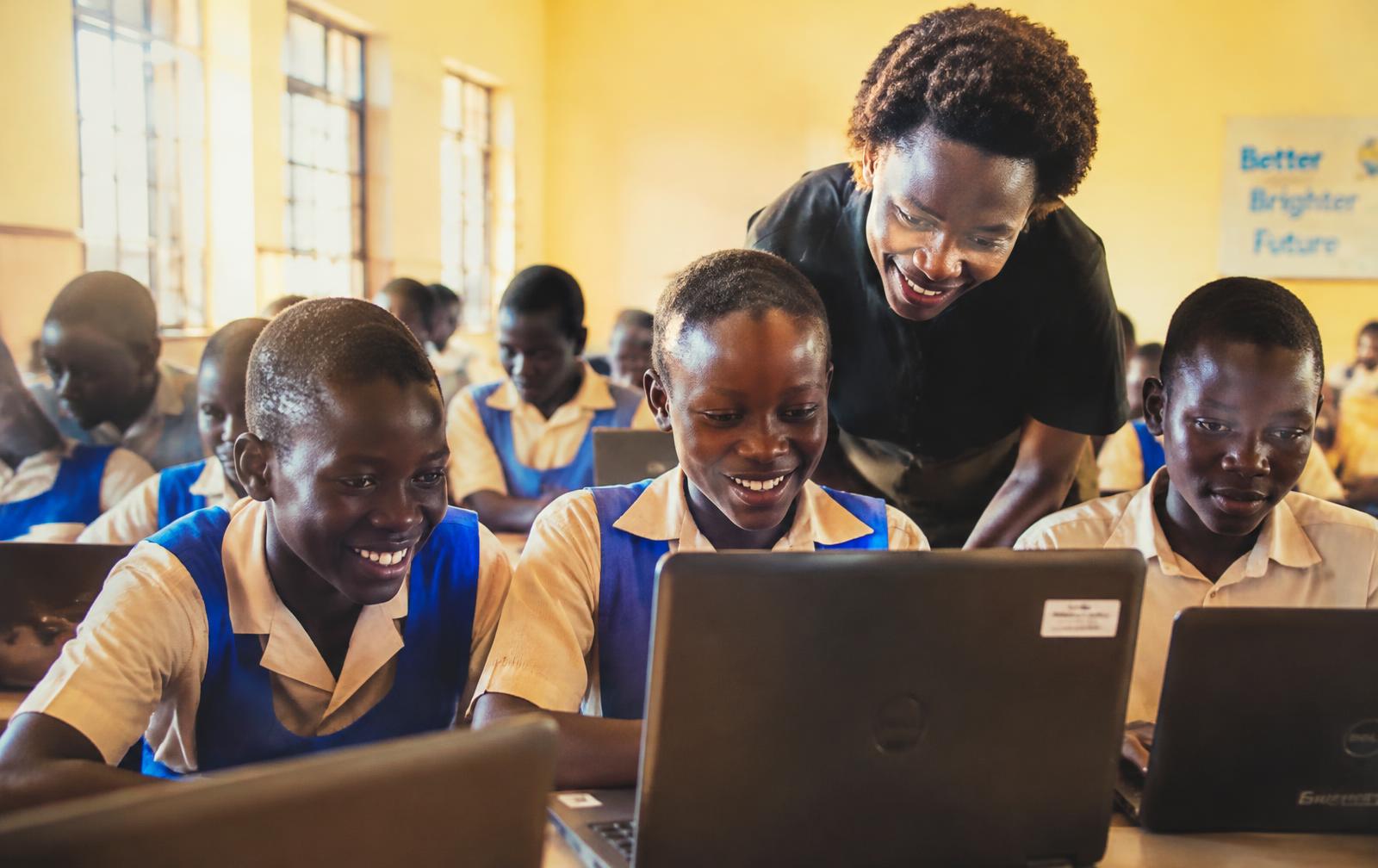Students learning on laptops with their teacher